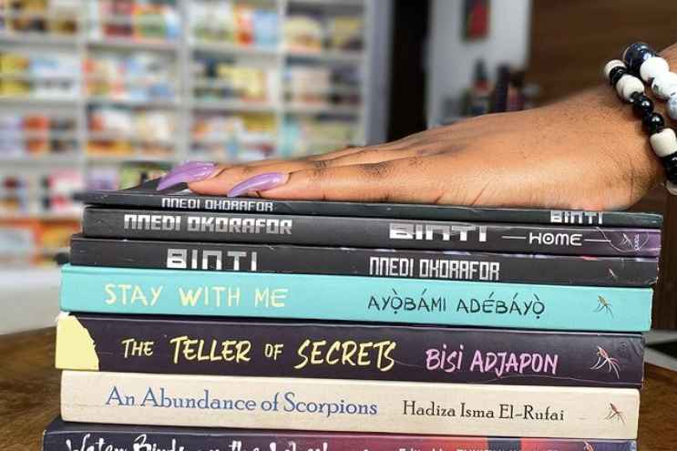 This photo shows a hand on a stack of books inside the Ouida bookstore. Credit: Ouida.