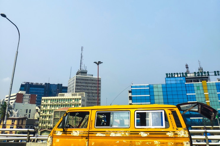 A moving danfo against a Lagos skyline. Credit: Babatunde Olajide / Unsplash