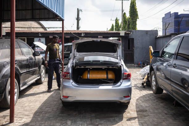 Tajudeen Esan stands by a car displaying a gas bottle to convert it to gas combustion in City Mechanic, a Compressed Natural Gas (CNG) center Lagos, on November 12, 2024. Credit: Olympia De Maismont / AFP / Getty Images